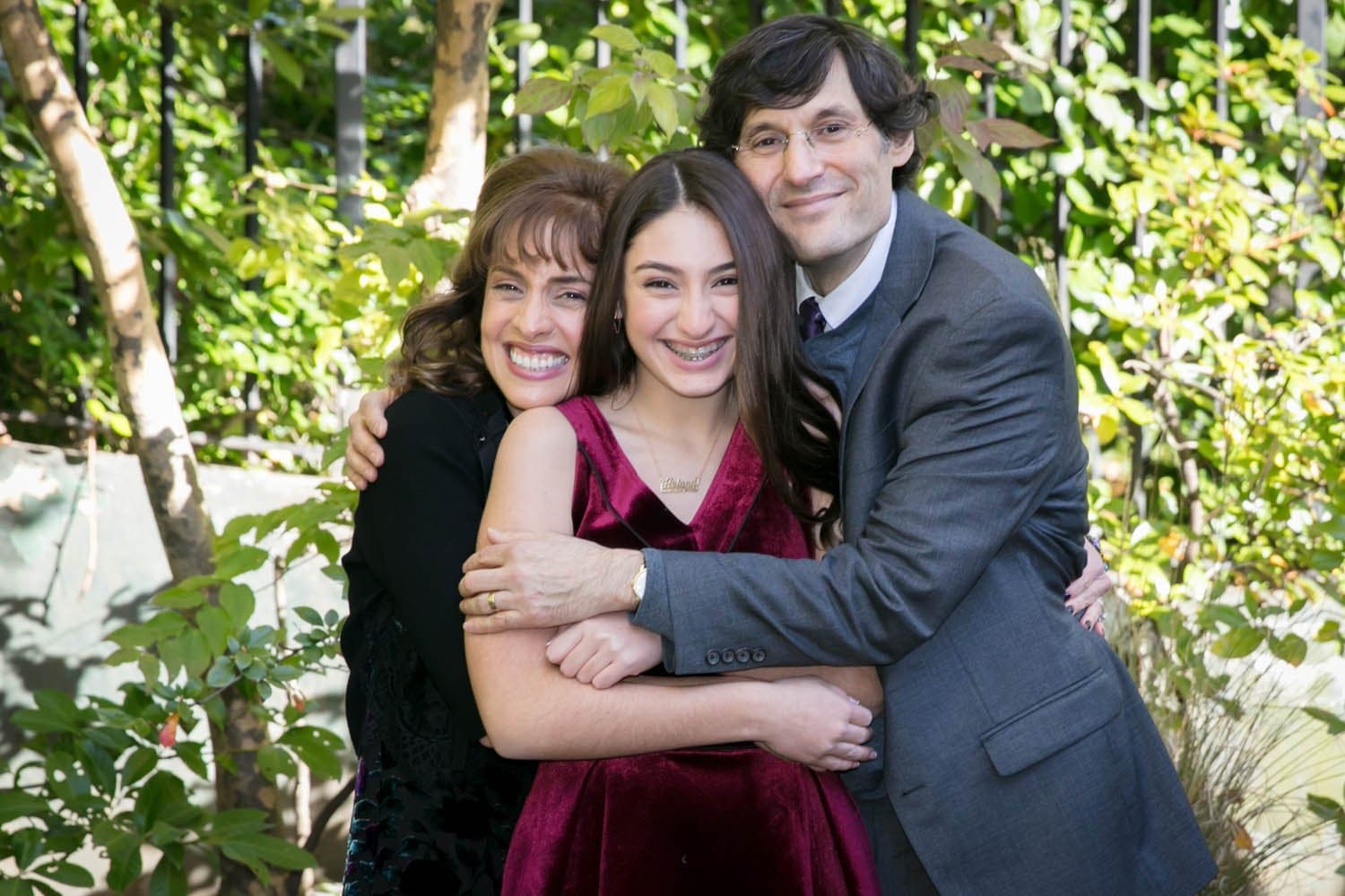 Mother, father and daughter hugging in a garden