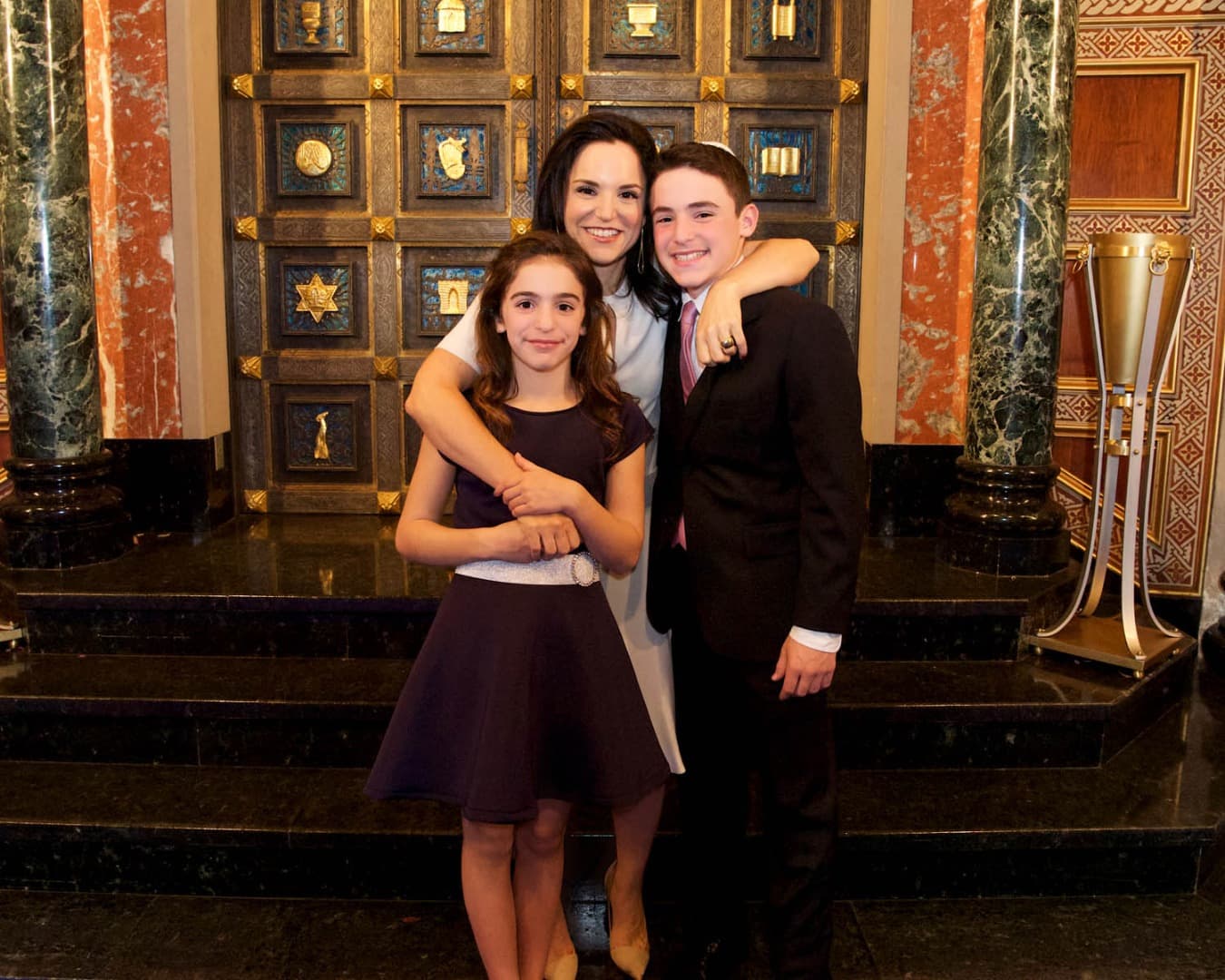Mother with her son and daughter in front of the synagogue ark
