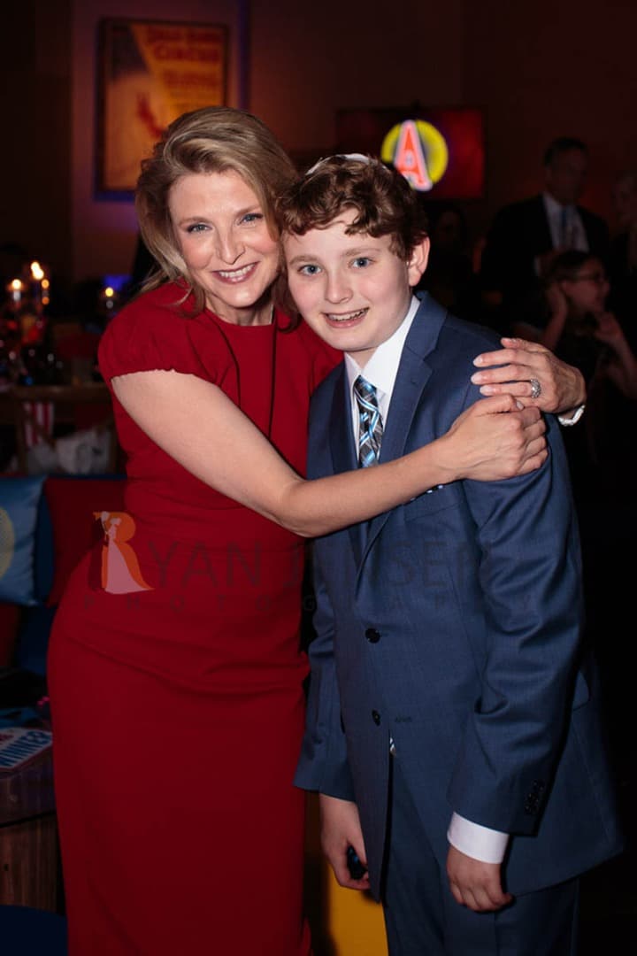 Woman in a red dress hugging a boy in a blue suit