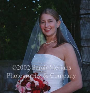 Bride in a veil holding red and pink roses